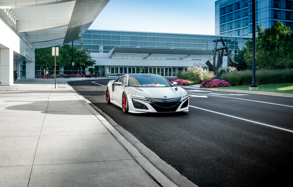 A white sports car is driving down a city street