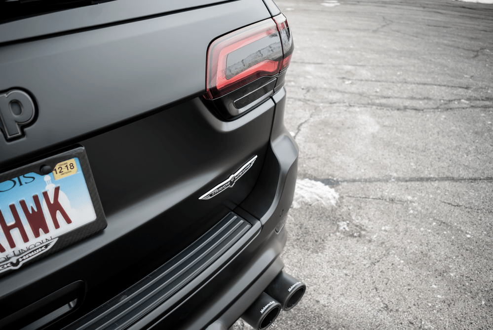 A black jeep with a license plate that says hwk