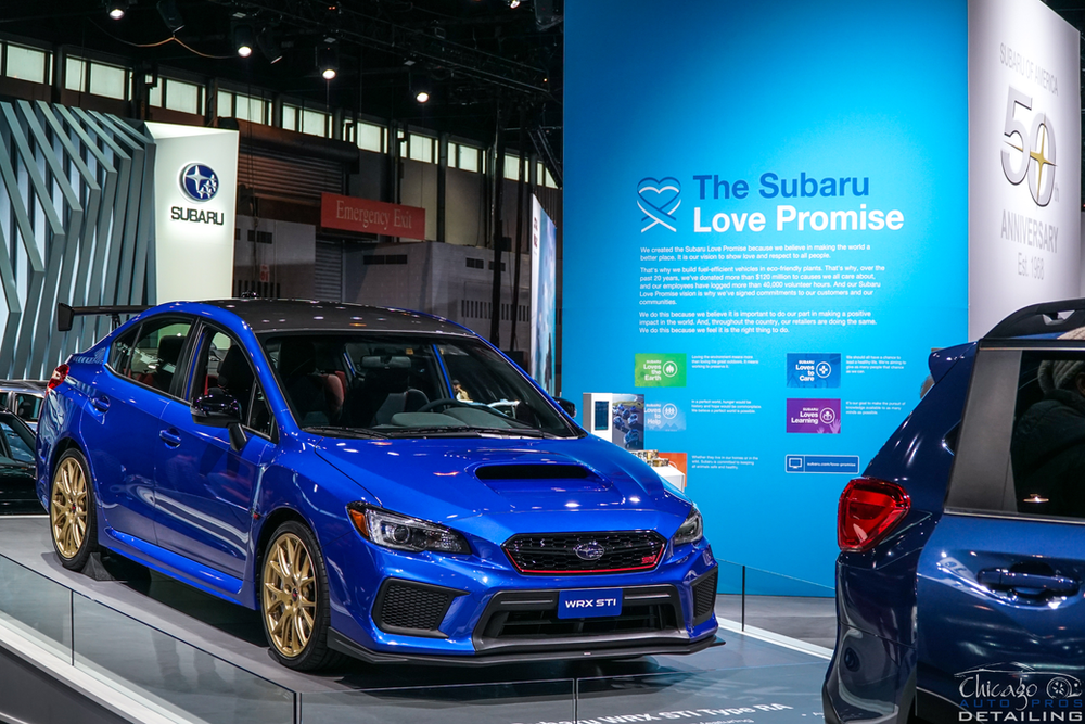 A blue subaru wrx sti is on display at a car show.