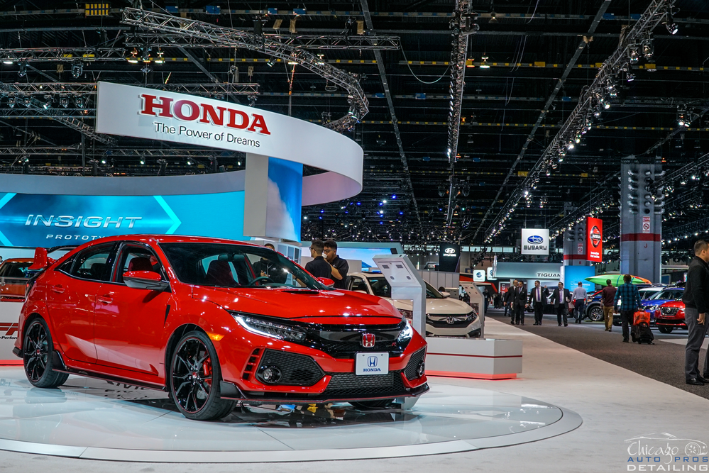 A red honda civic type r is on display at a car show.