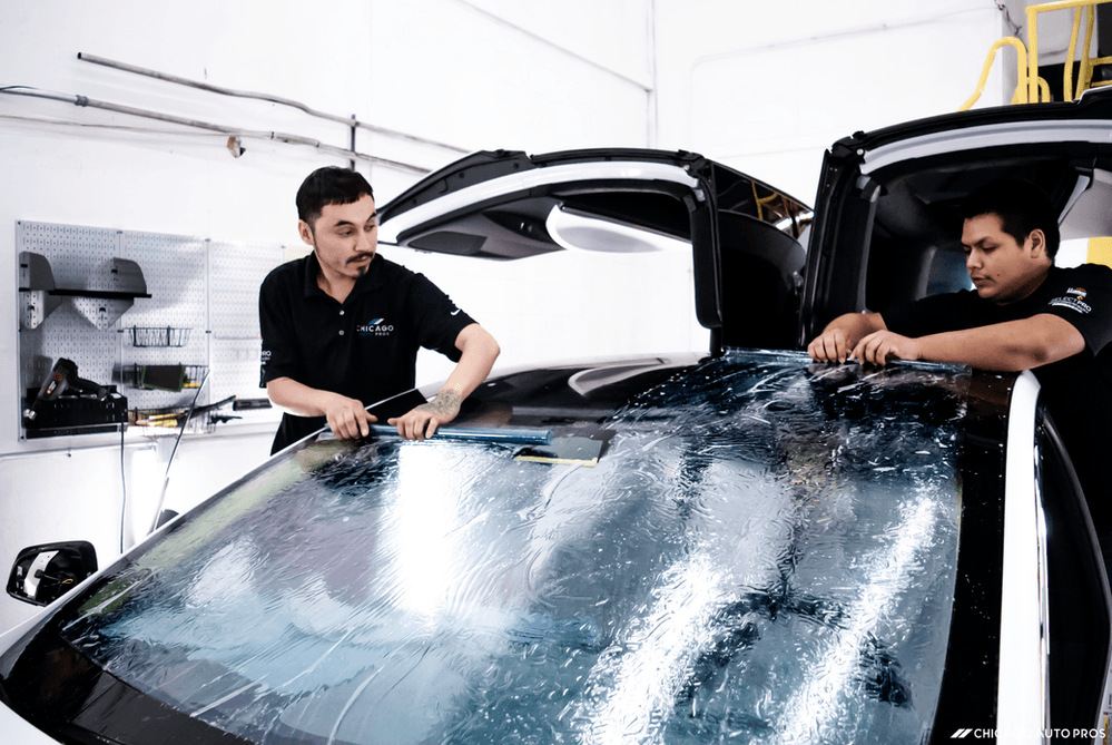 Two men are working on a car in a garage.