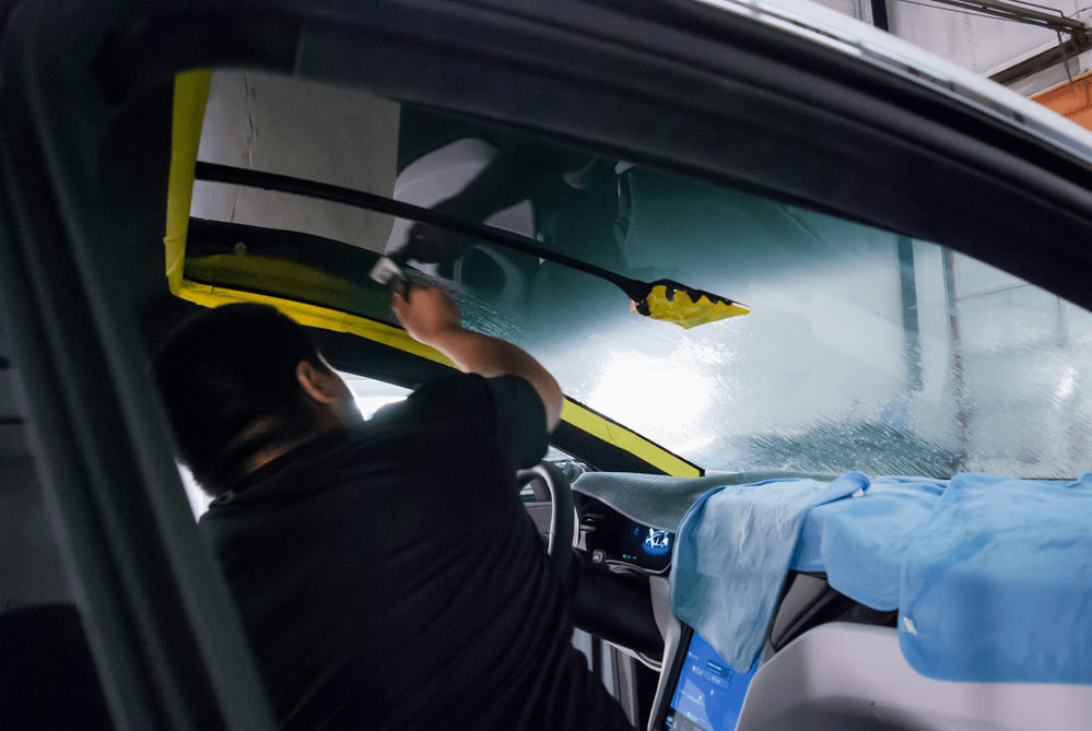 A man is cleaning the windshield of a car.