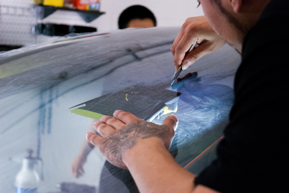 A man is applying tinted glass to a car windshield.