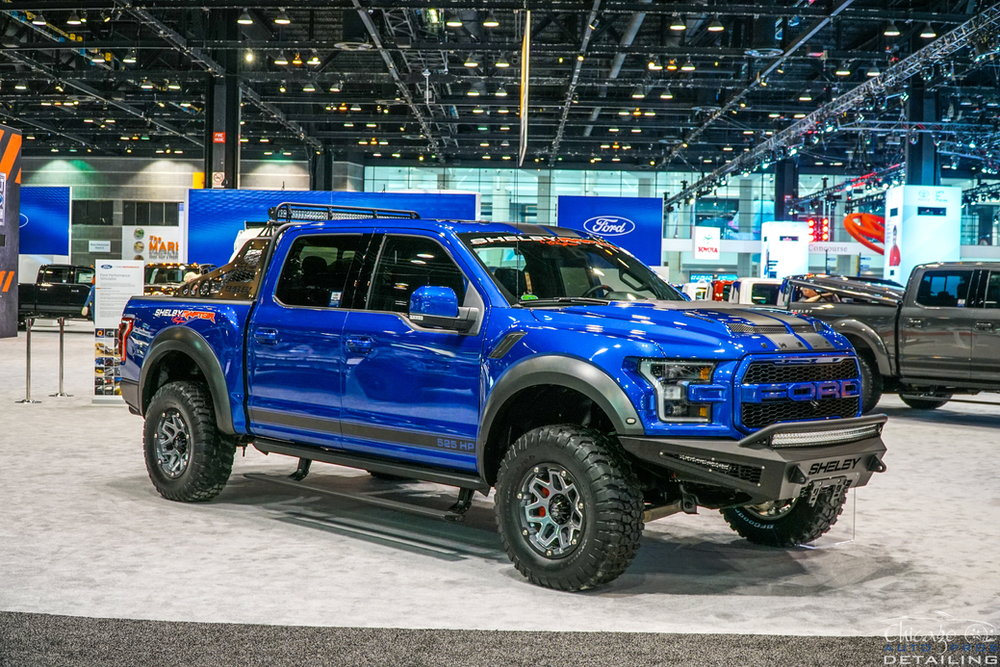 A blue ford raptor is on display at a car show.