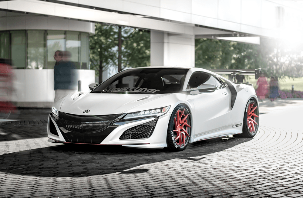 A white sports car with red wheels is parked in front of a building.