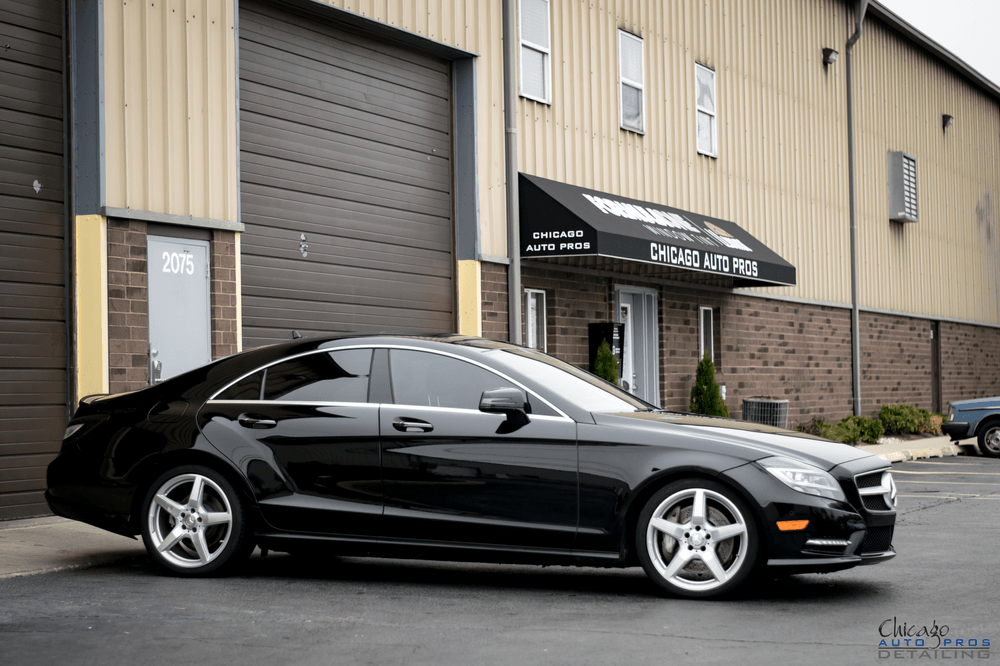 A black mercedes benz cls is parked in front of a building.