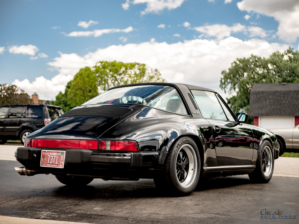 A black porsche targa is parked in a parking lot.