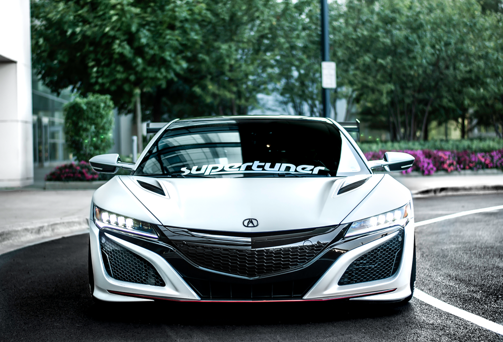 A white sports car is parked on the side of the road.