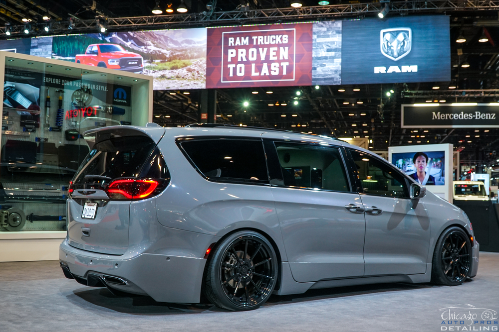 A gray minivan is parked in front of a sign that says rim trucks proven to last.