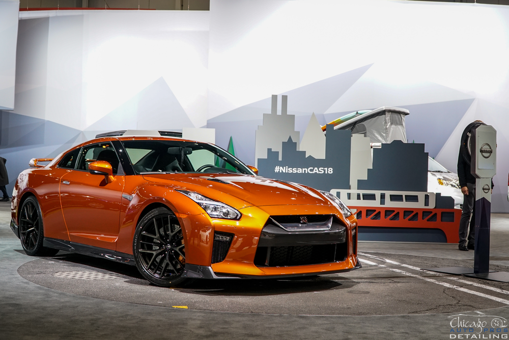 A nissan gt r is parked in a parking lot at a car show.