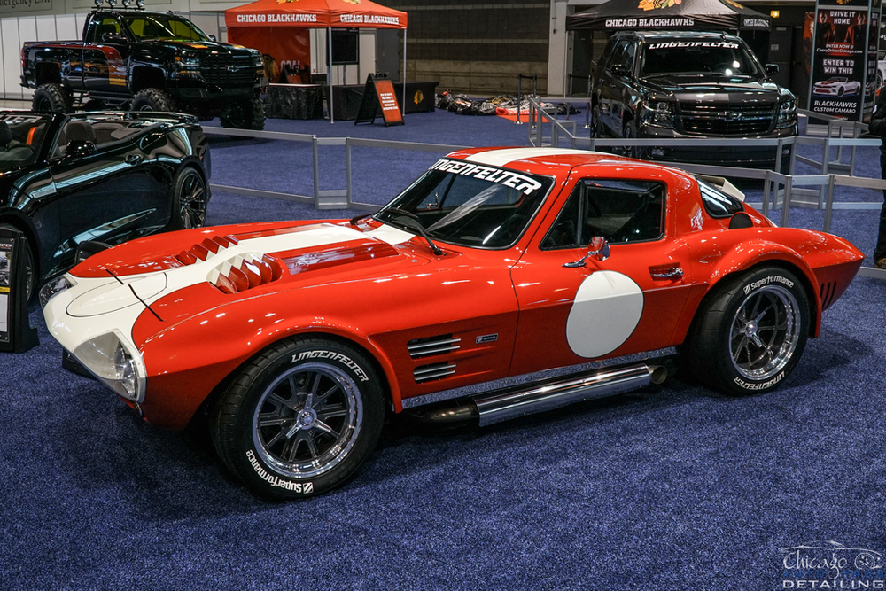 A red and white corvette is on display at a car show.