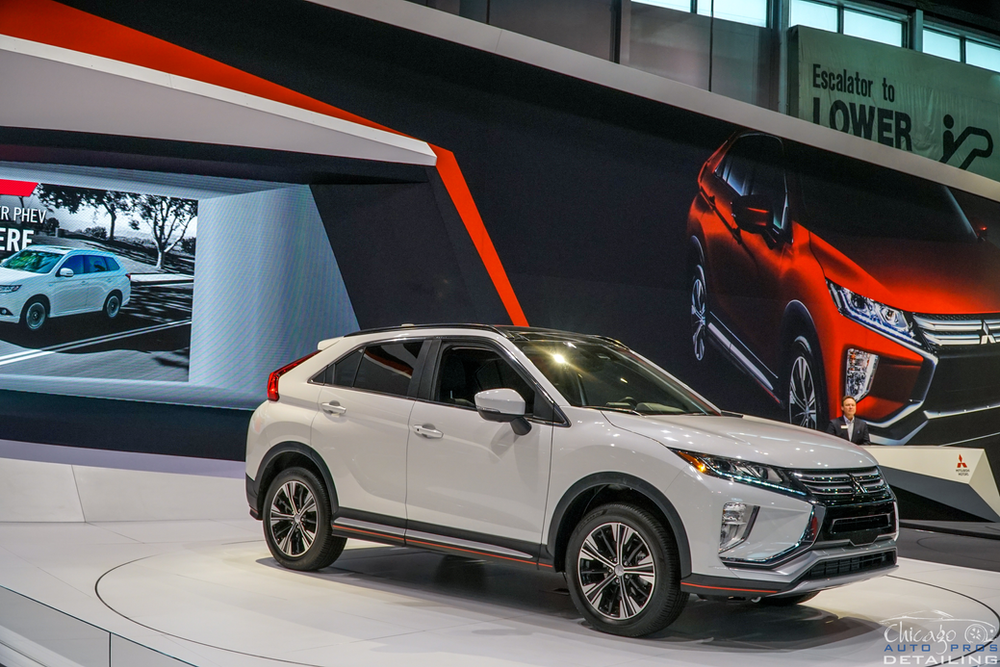 A white mitsubishi eclipse cross is on display at a car show.