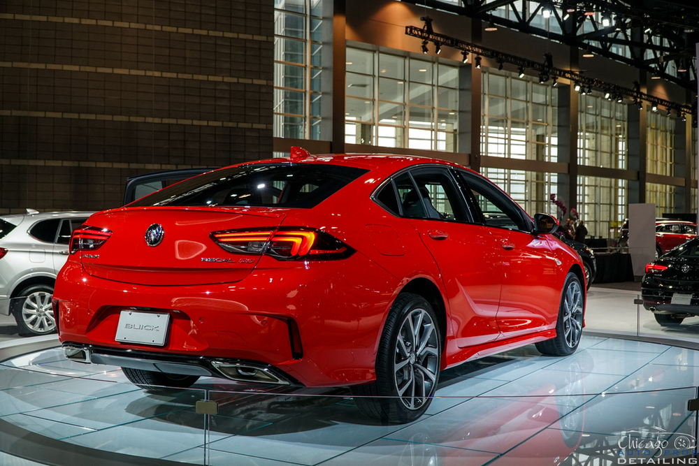 A red car is on display at a car show.