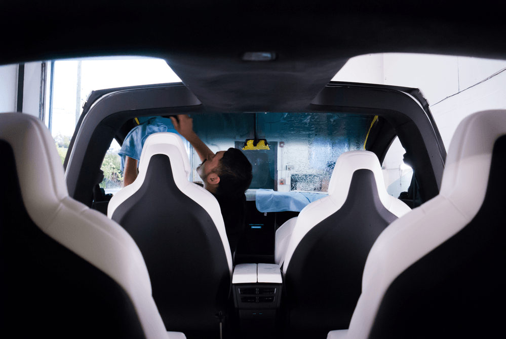 A man is cleaning the windshield of a tesla model x.