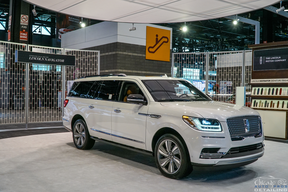 A white lincoln navigator is on display at a car show.