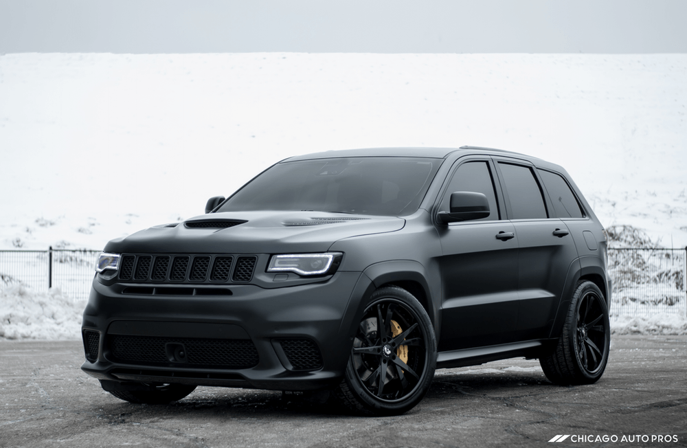 A black jeep grand cherokee is parked in the snow.