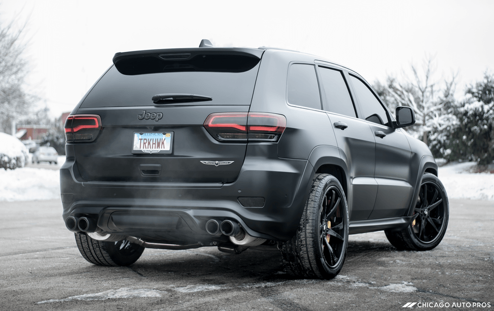 A black jeep grand cherokee is parked in the snow.