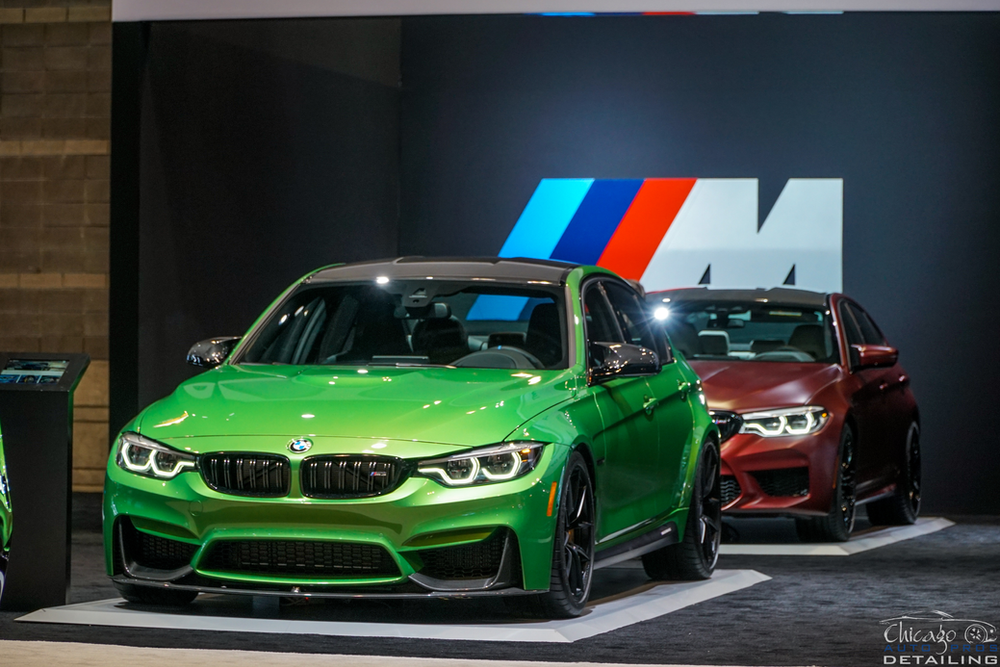 A green bmw m3 is parked next to a red bmw m5.