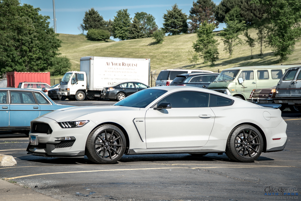 A white ford mustang is parked in a parking lot.