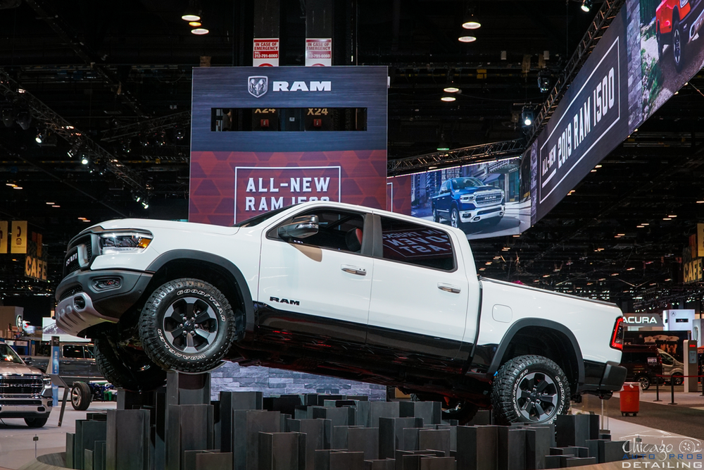 A white ram truck is on display at a car show.
