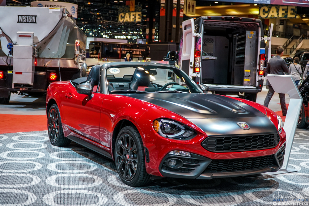 A red convertible car is on display at a car show.