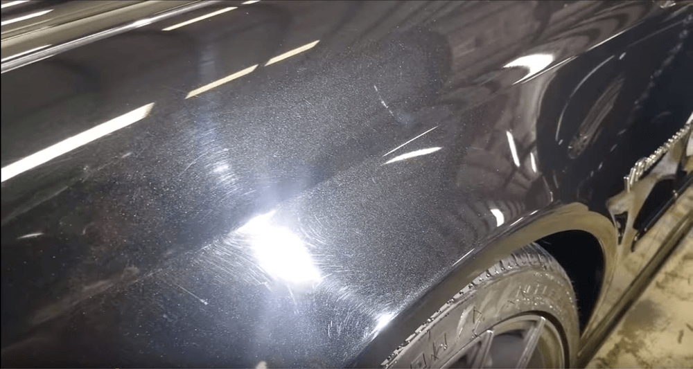 A close up of a black car 's fender in a garage.