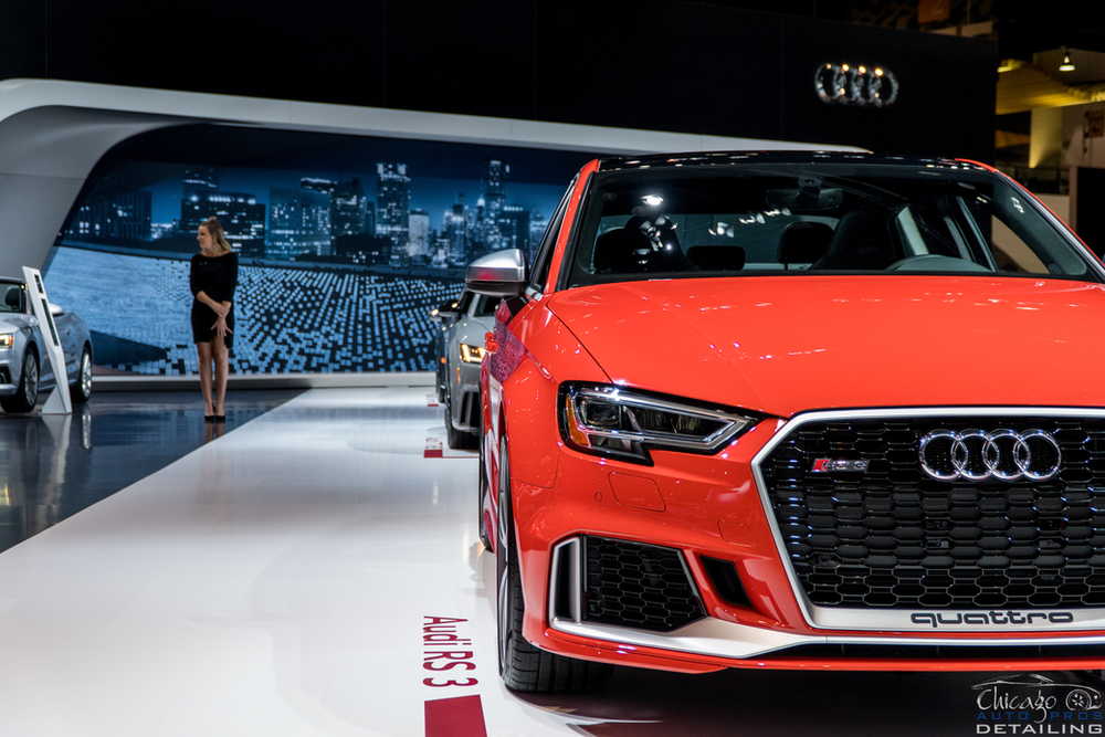 A red audi rs3 is on display at a car show.