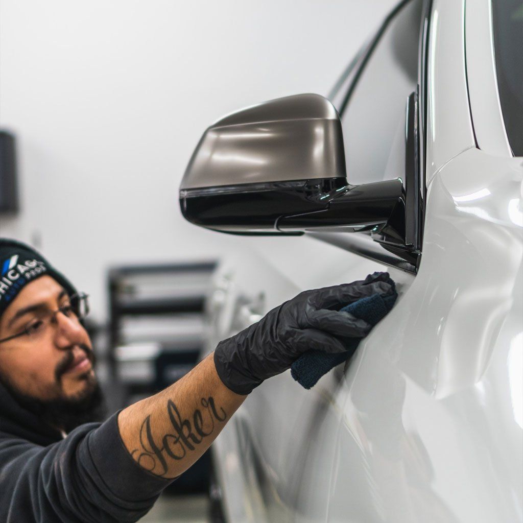 A man with a tattoo on his arm is cleaning a car.