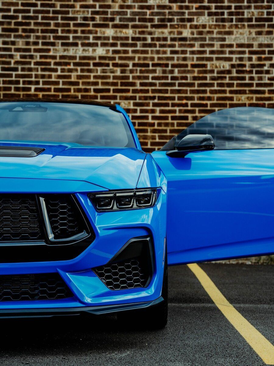 A blue sports car is parked in a parking lot with its doors open.