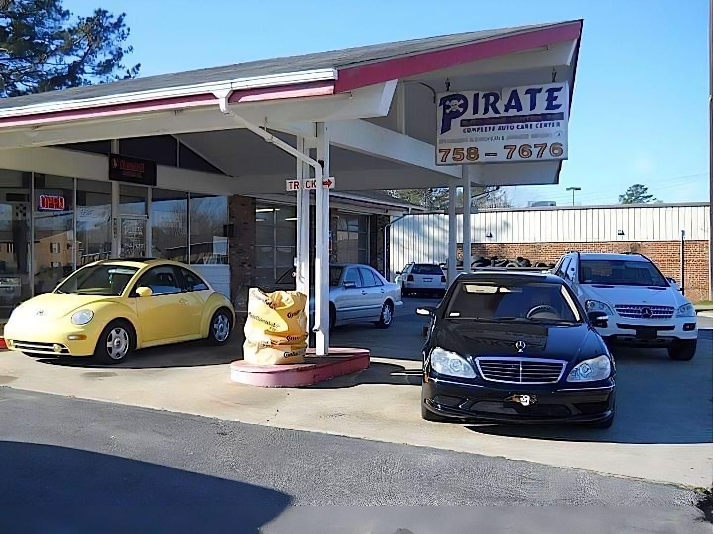 Several cars are parked in front of a pirate car dealership