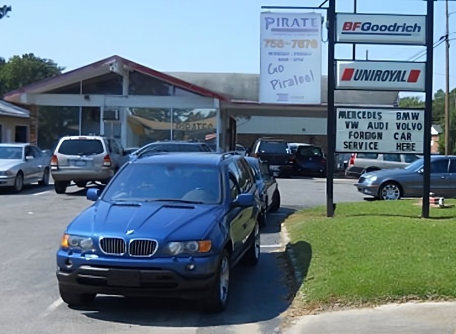 A blue bmw is parked in front of a pirate car dealership