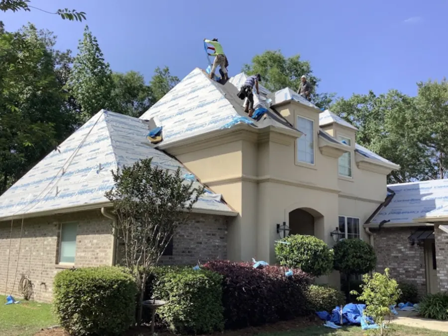 A group of people are working on the roof of a house.