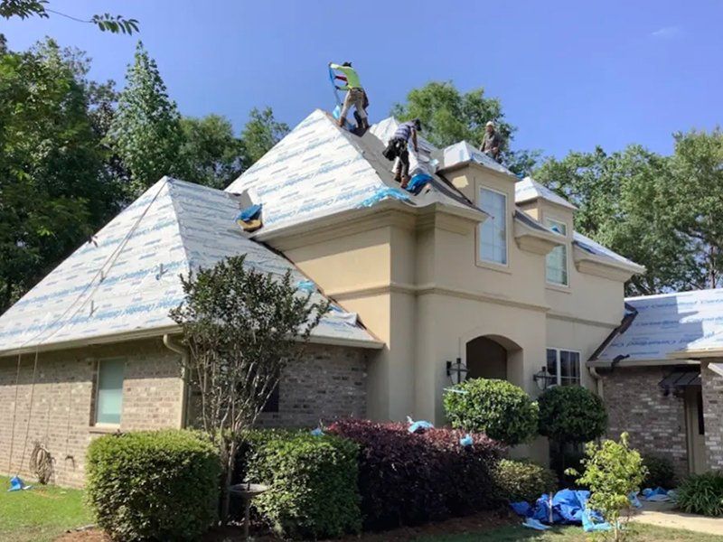 A group of people are working on the roof of a large house.