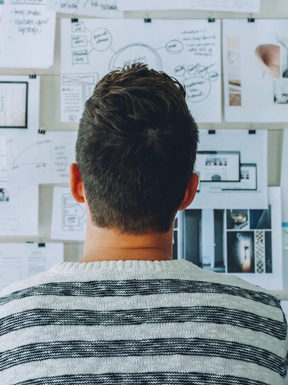 A man standing in front of a board with papers stuck to it planning a marketing and expo strategy for his brand