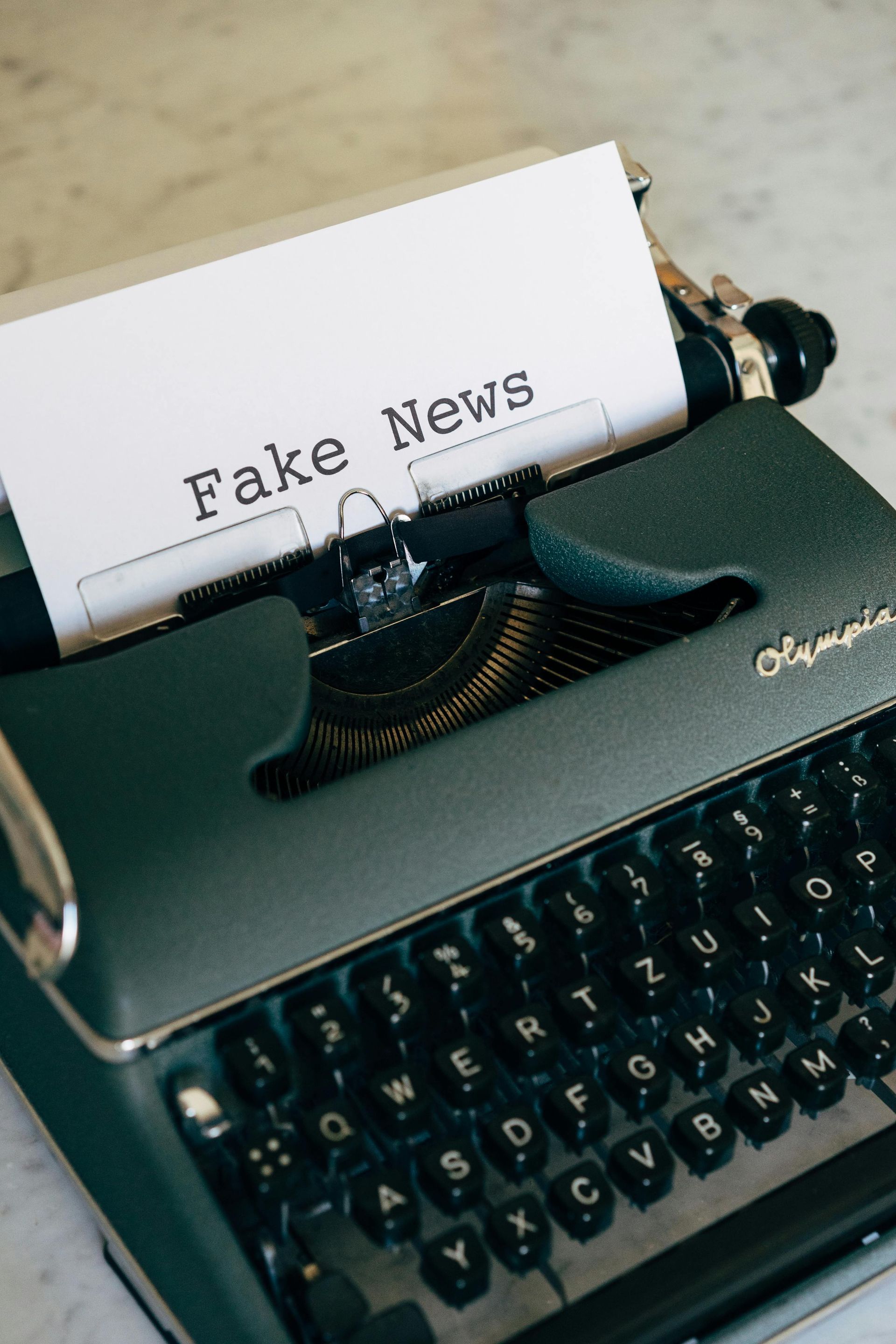 An old school typewriter that has a page in it and the title on the page says Fake News.