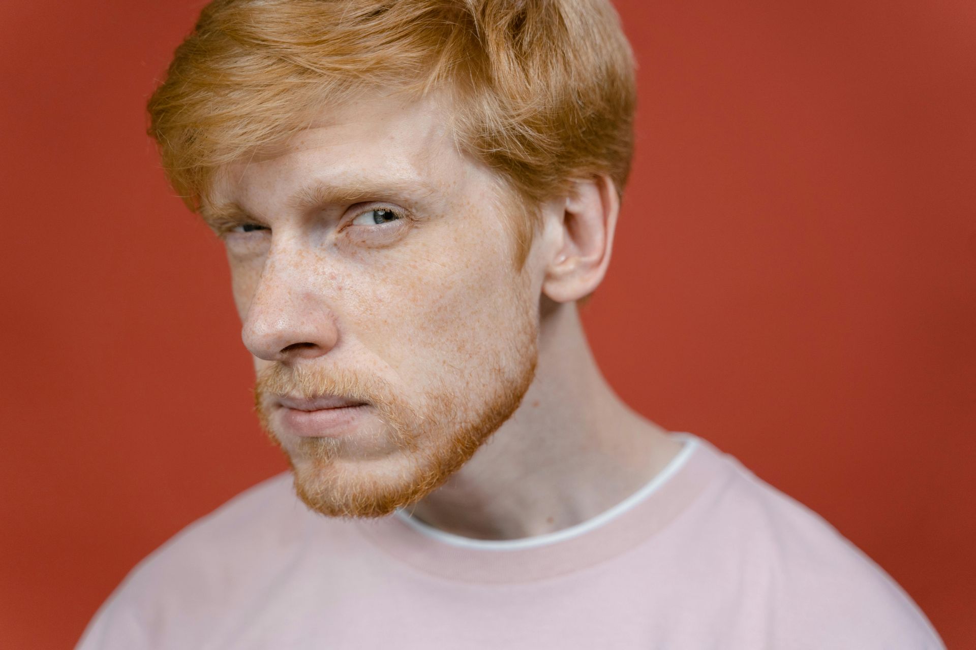 A white male with ginger hair looking at the camera with a skeptical look on his face that shows concern around the ethics of Ai