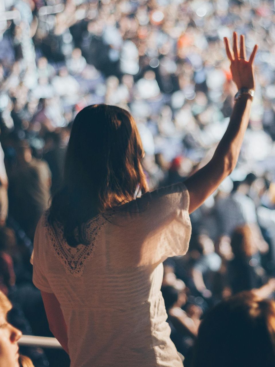 A person standing with their hand up in a crowd of people