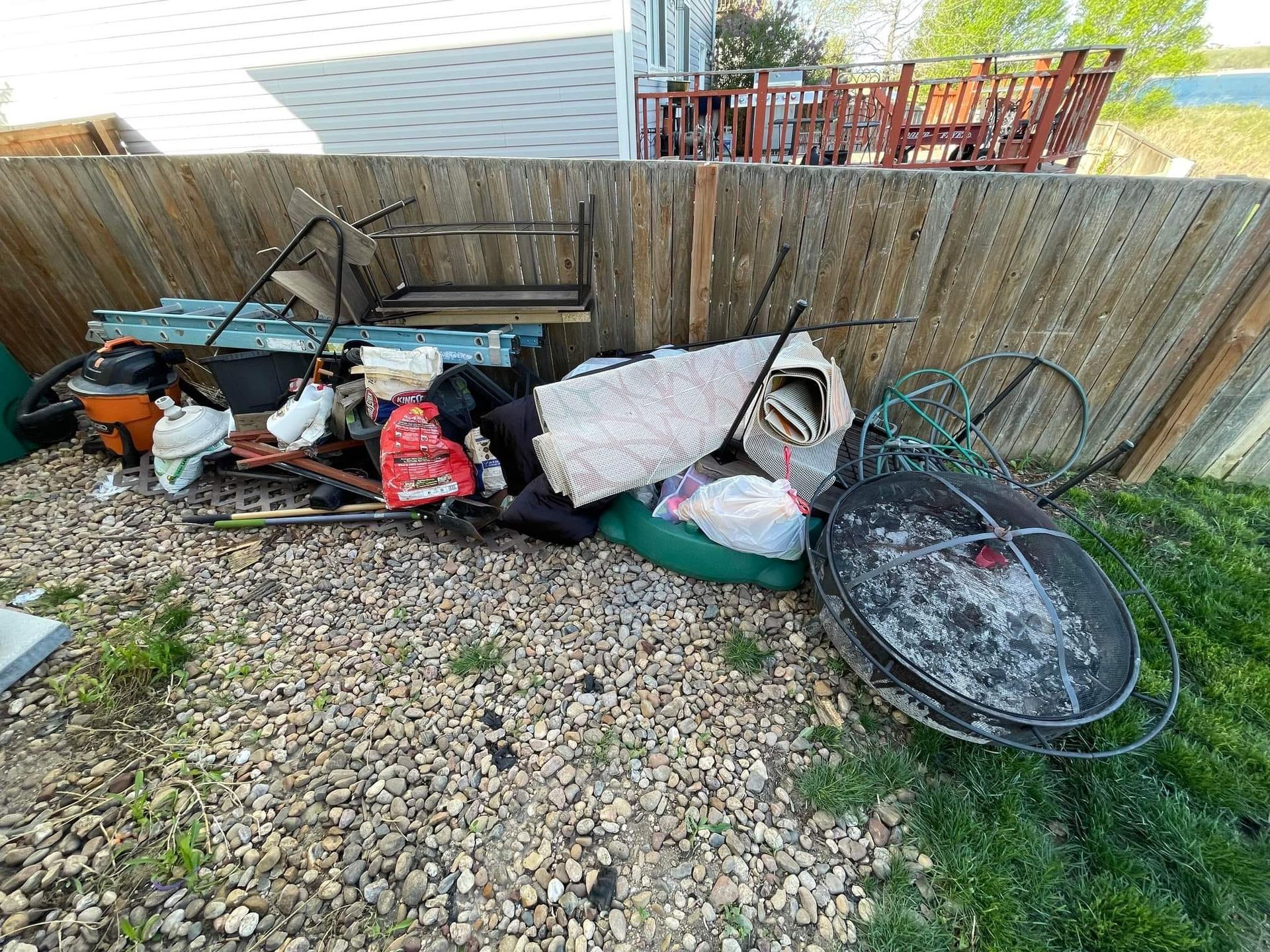 A pile of trash is sitting on the ground in front of a wooden fence.