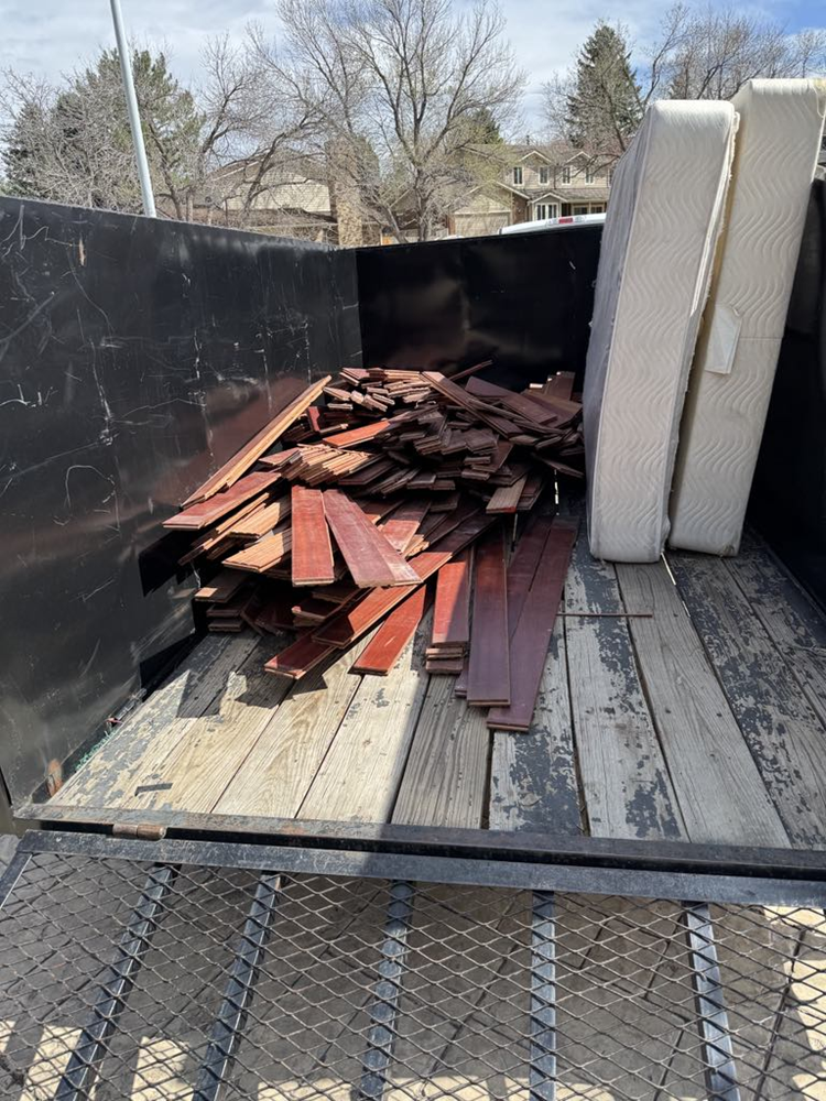 A dumpster filled with wood and a mattress.