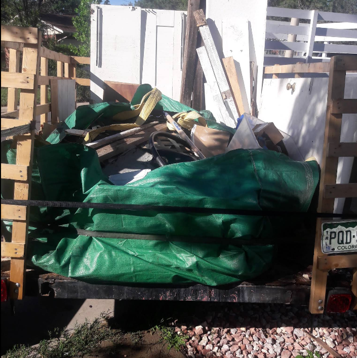 A green tarp is on the back of a truck with a license plate that says pod