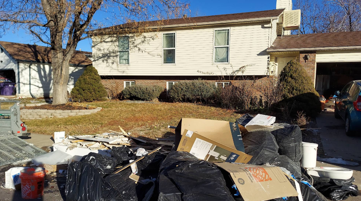 A pile of trash is in front of a house.