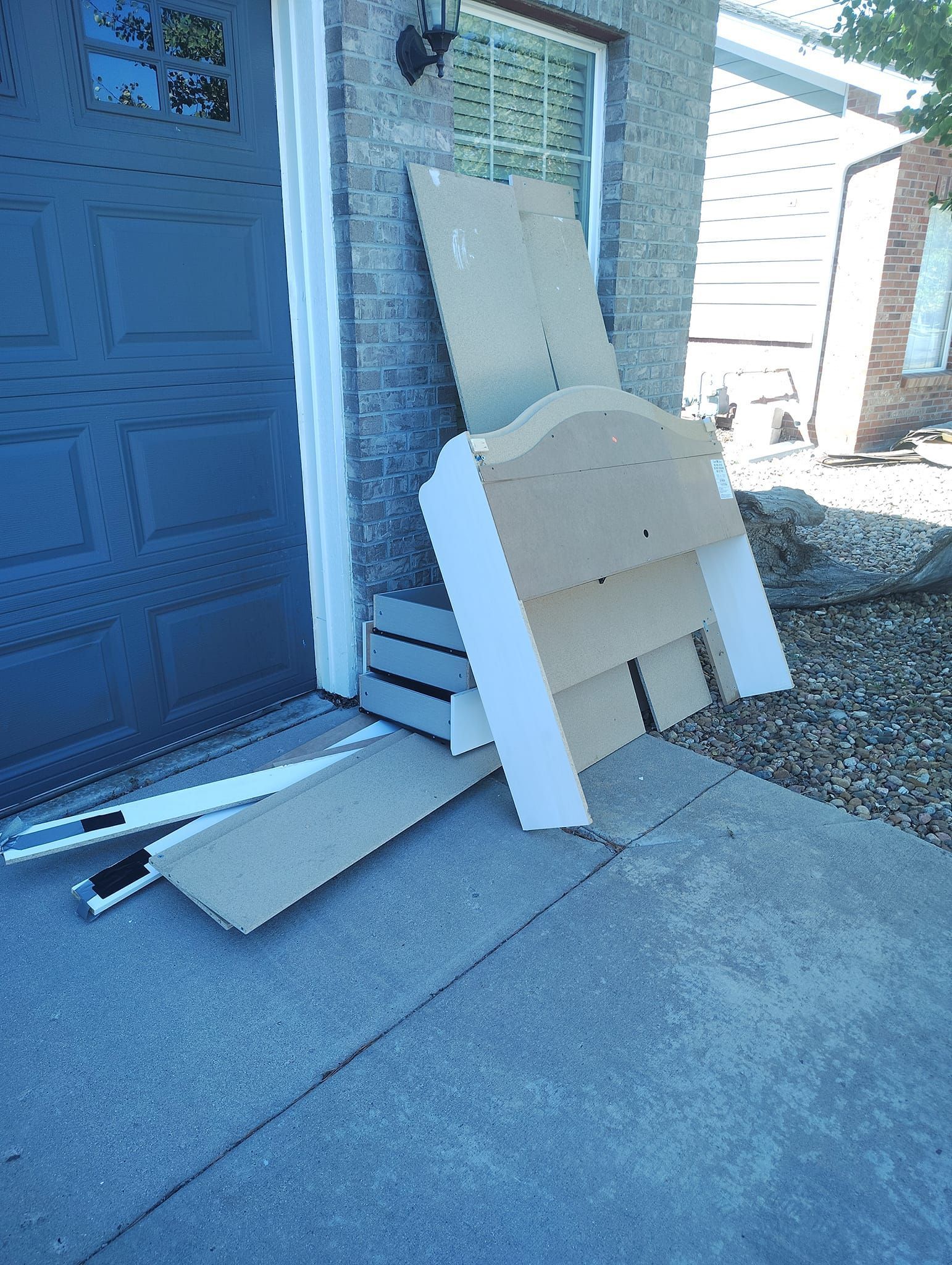 A pile of wood is sitting on the sidewalk in front of a garage door.
