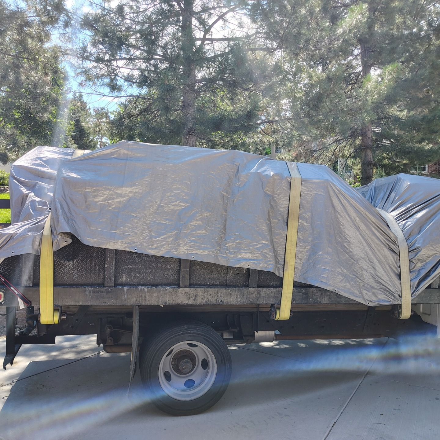 A truck with a tarp on top of it is parked on the side of the road.