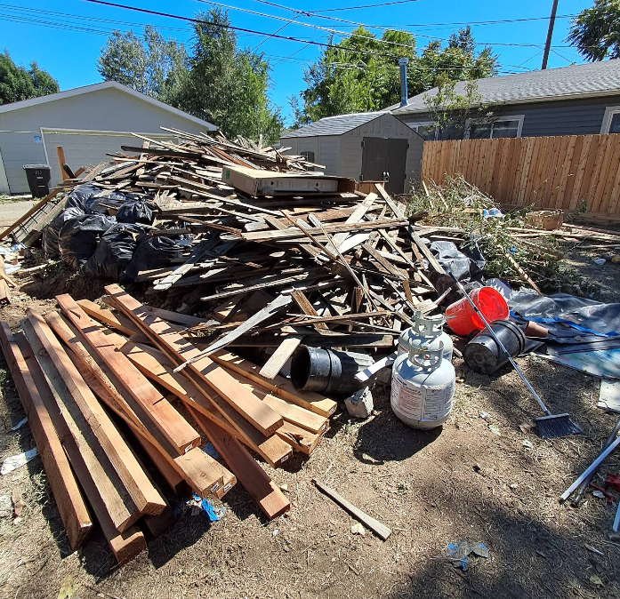 A pile of wood is sitting on the ground in front of a house.