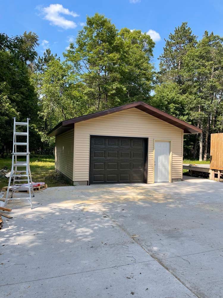 A garage with a black door and a ladder in front of it