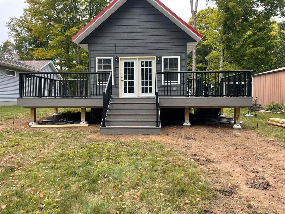 A small house with a large deck in front of it.