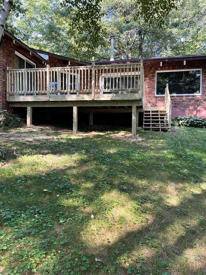 A brick house with a large wooden deck in the backyard.