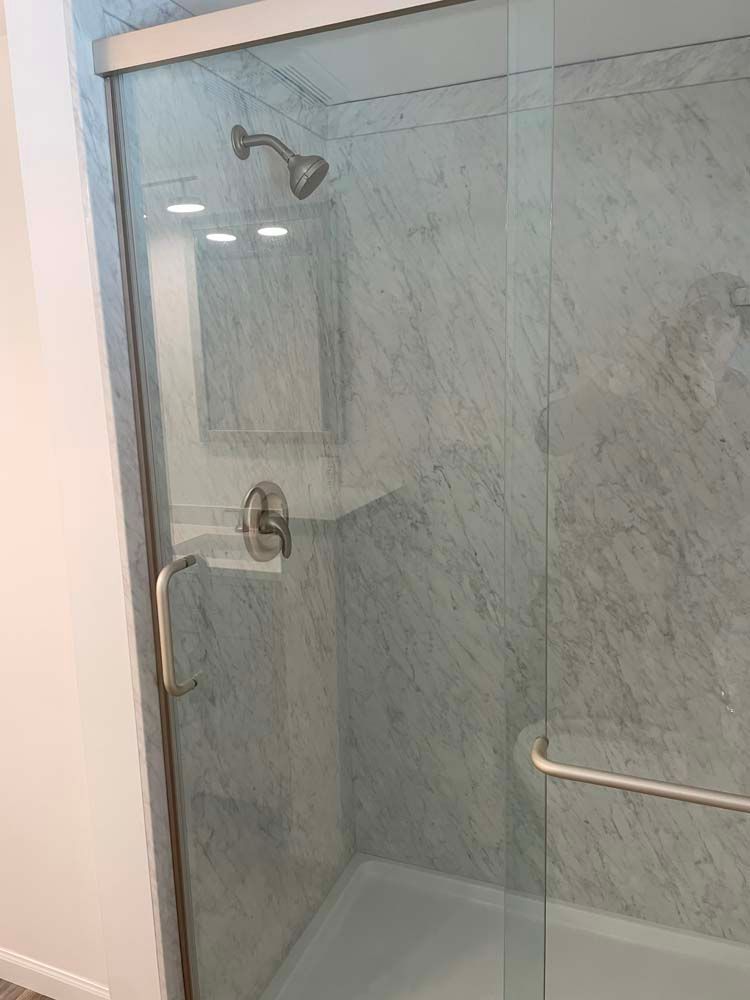 A bathroom with a sliding glass shower door and a bathtub.