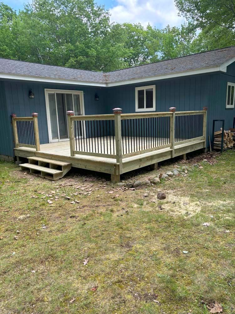 A blue house with a wooden deck in front of it.