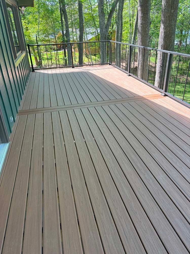 A wooden deck with a railing and trees in the background.